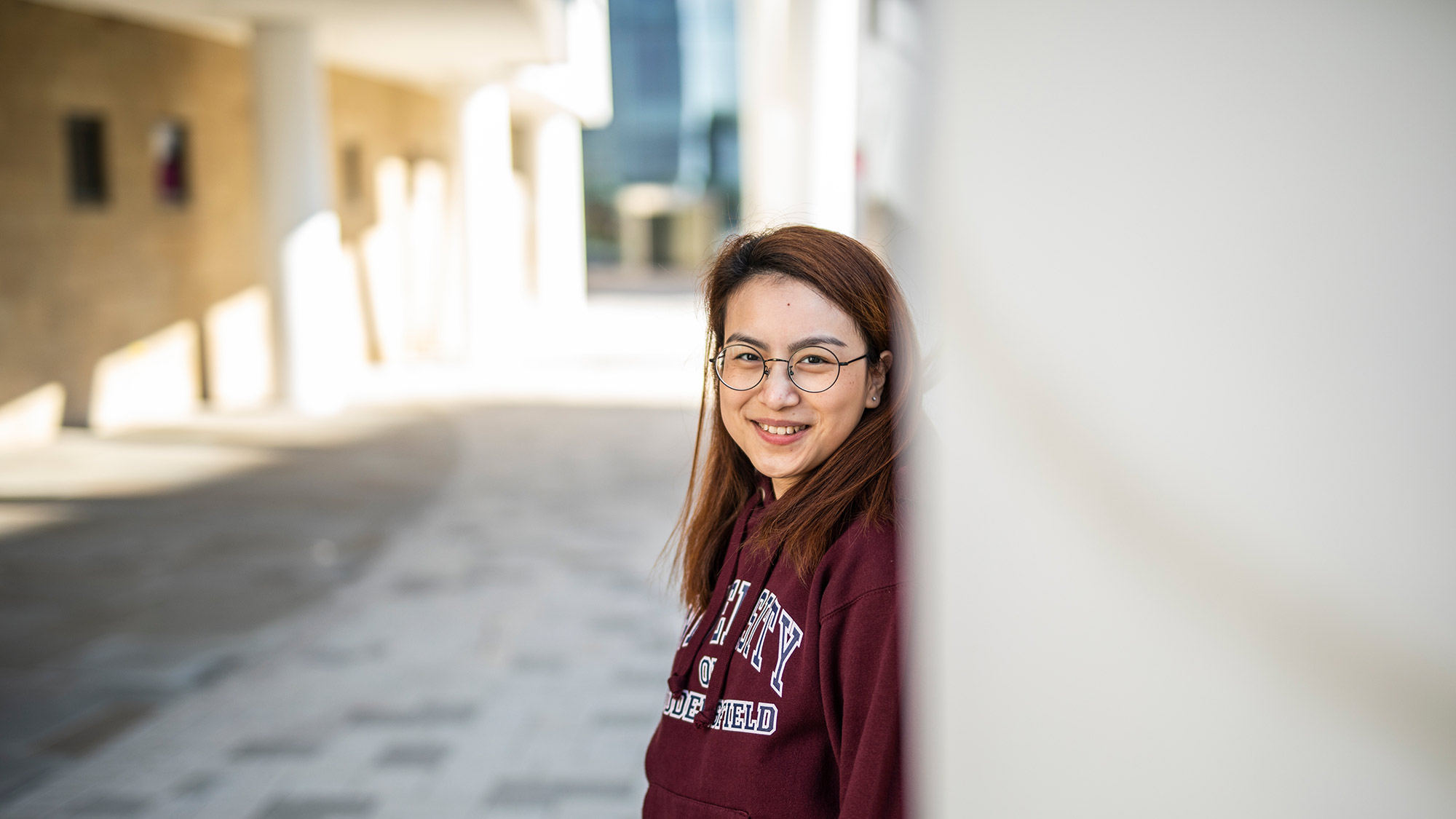 An international student stands for an image on the University plaza