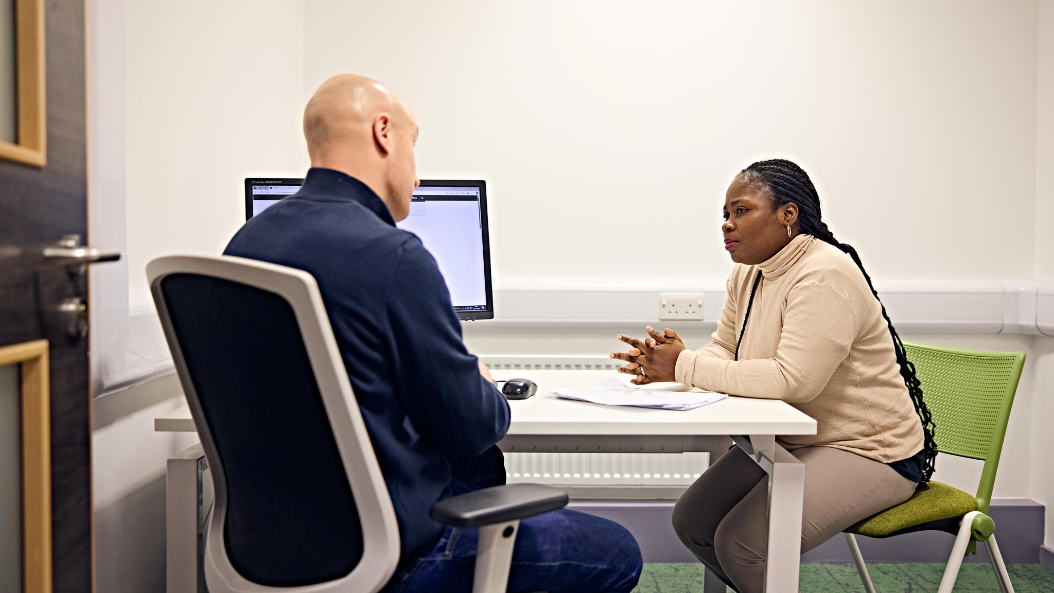 Two people sat at a desk talking to eachother
