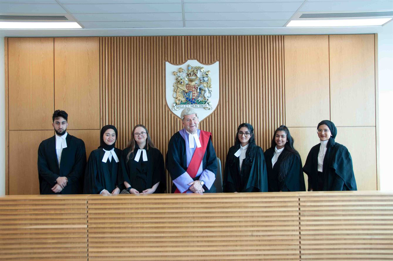 Law students with a judge in a mock courtroom doing a mooting competition