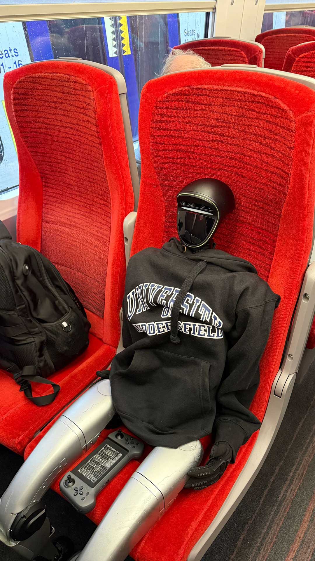 Harold the Robot sat on a red train char looking to be asleep.