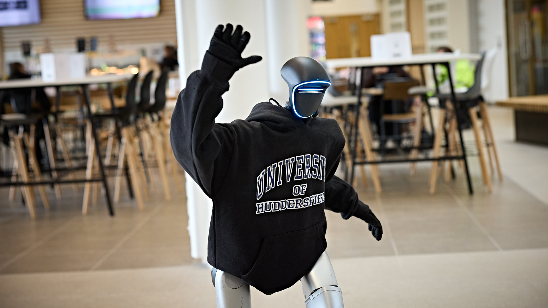 A humanoid robot wearing a hoodie and waving