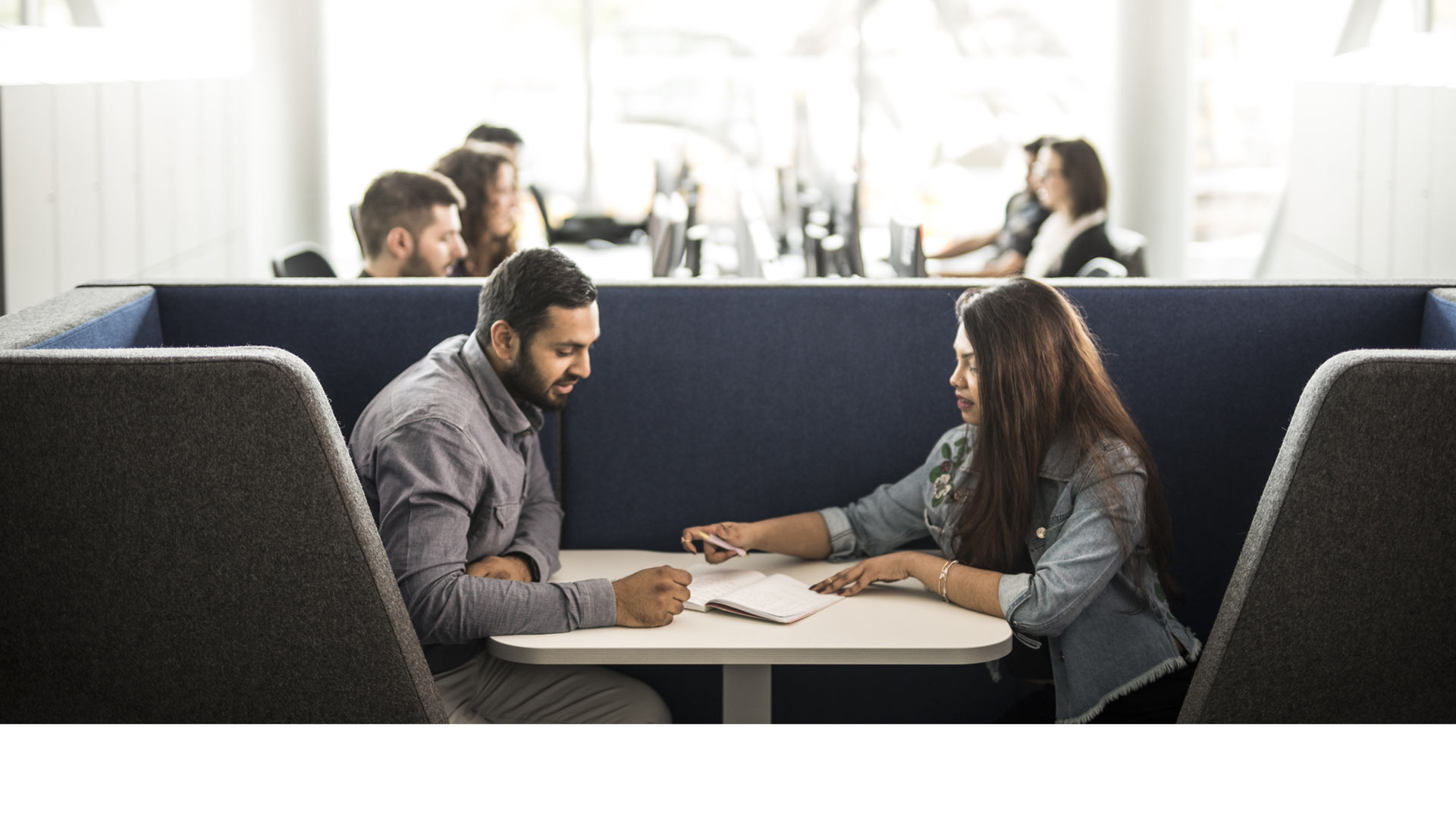 A header image of 2 people sat at a table to use on the new postgraduate pages.