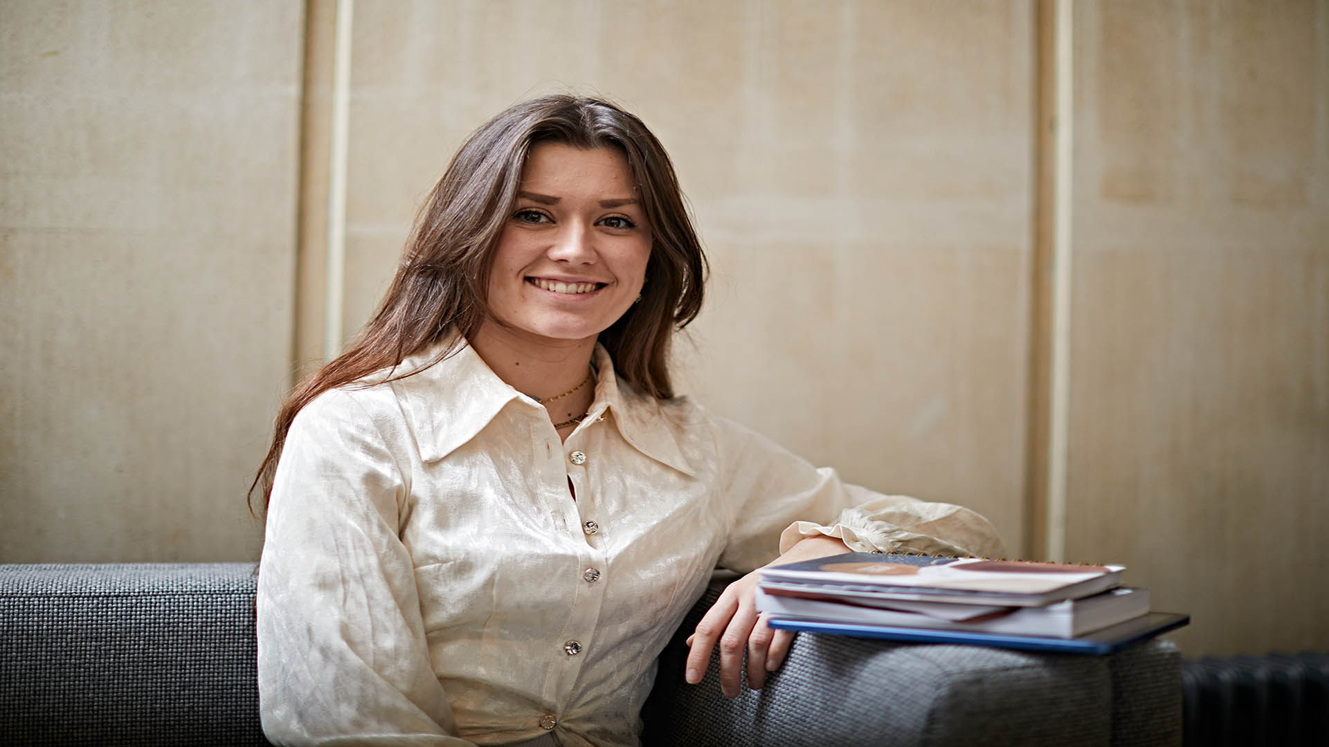 Emily smiling while sat on the sofa with books