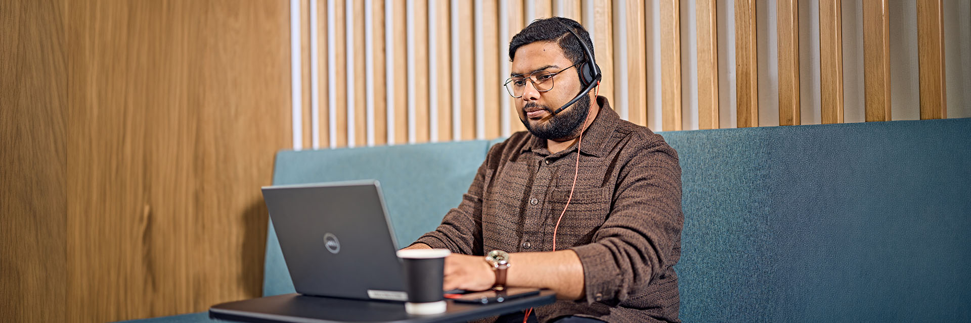 Student sitting in study space with a laptop wide