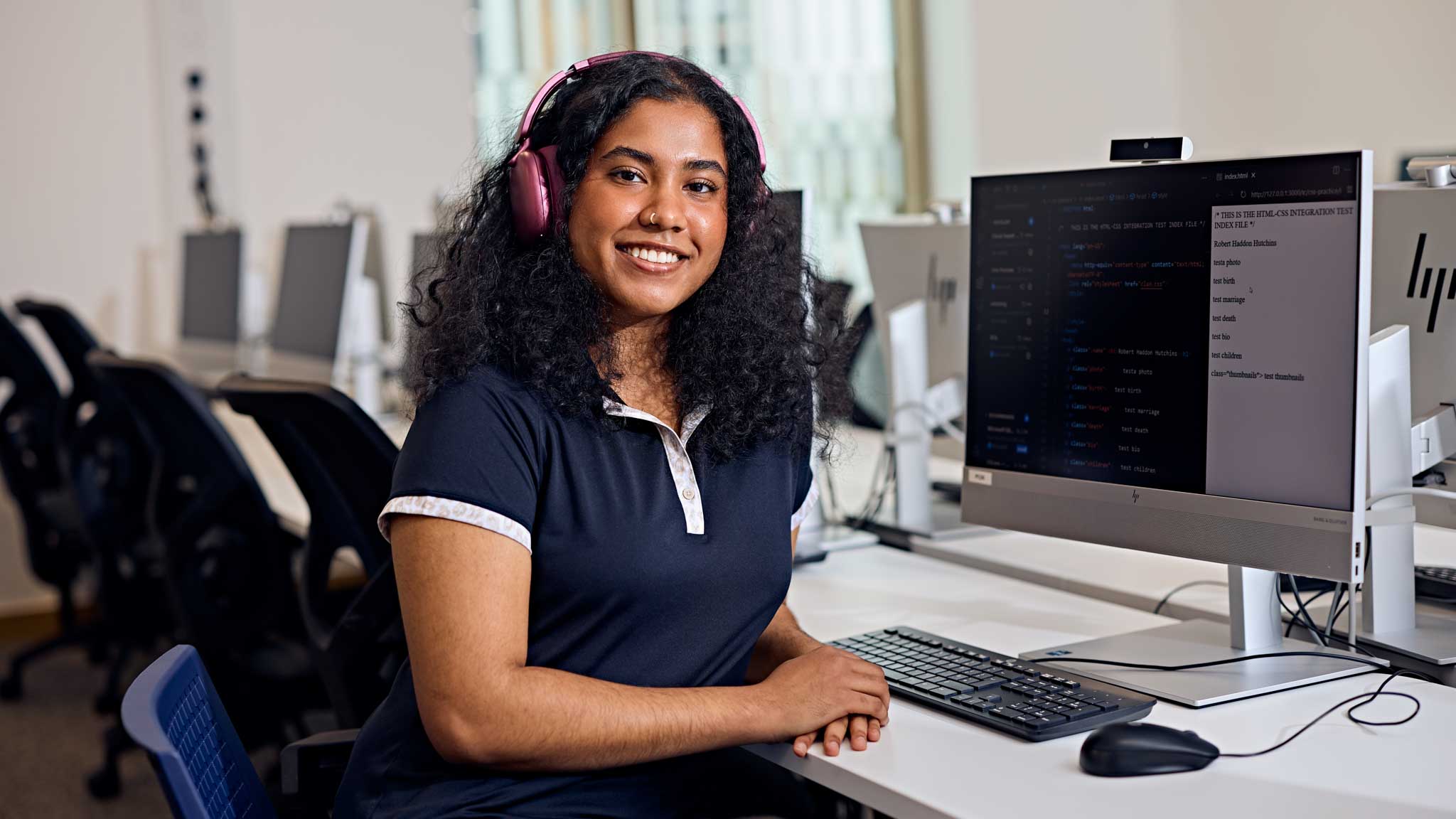 Student smiling at camera in front of a desktop