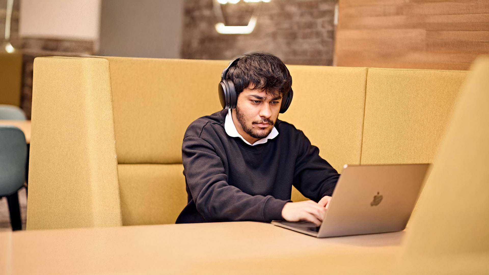 Male student working on a laptop in a common area