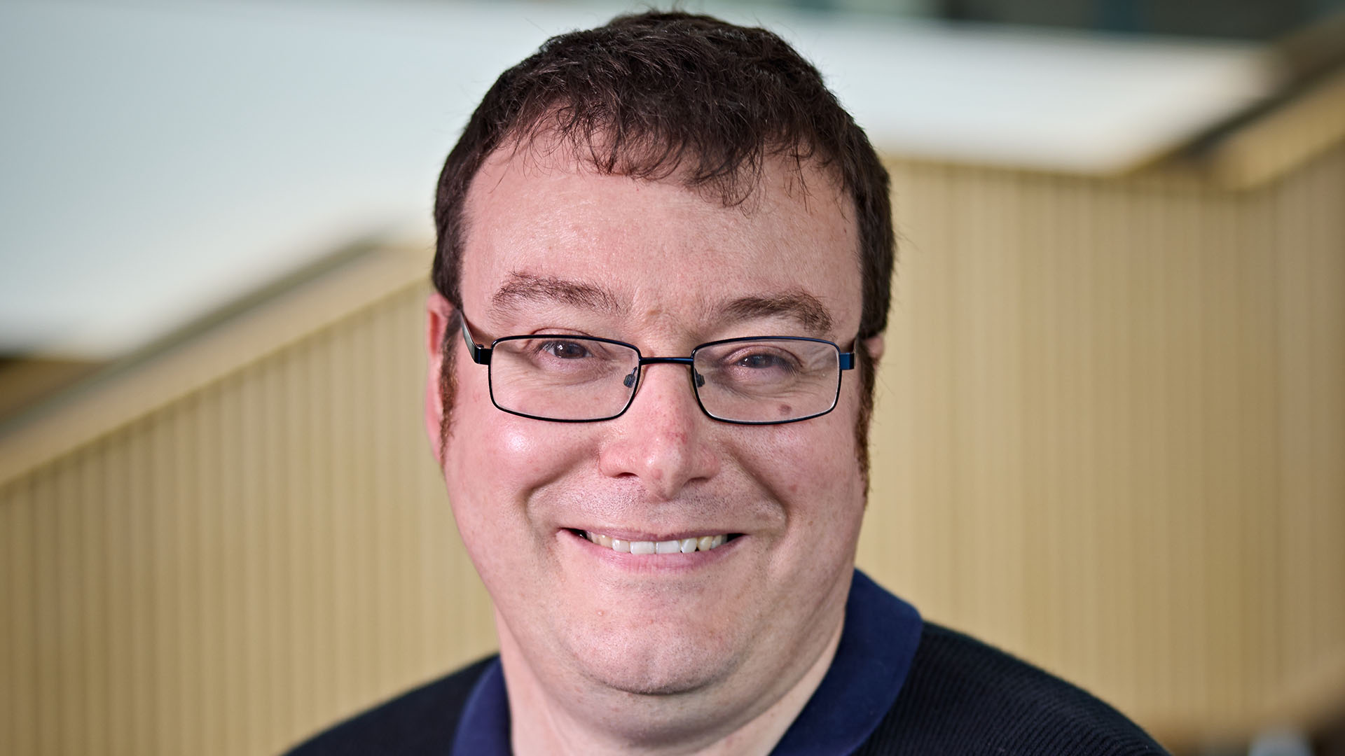 A headshot image of Jamie Halsall, he is smiling