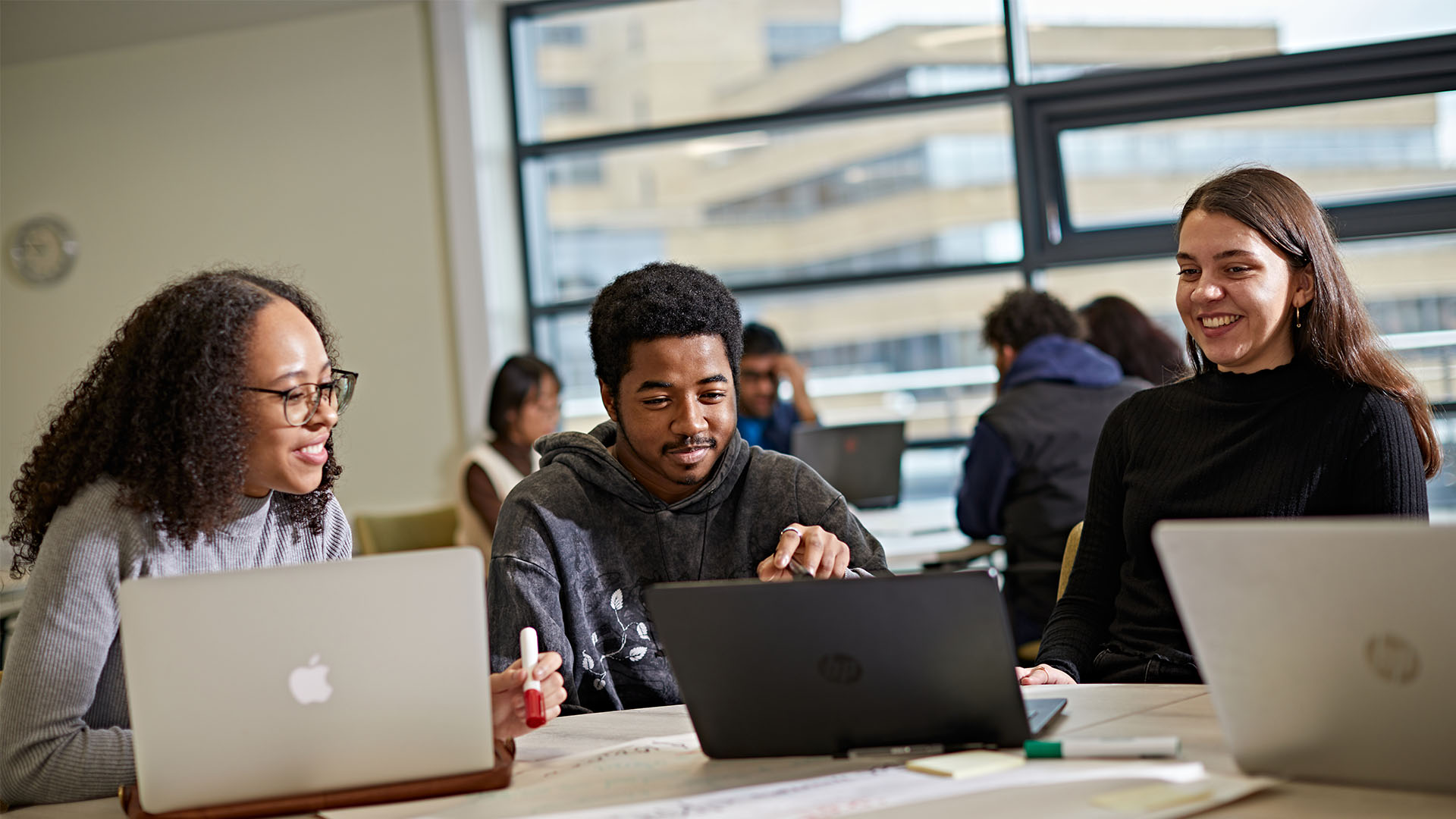Three students on laptops in classroom