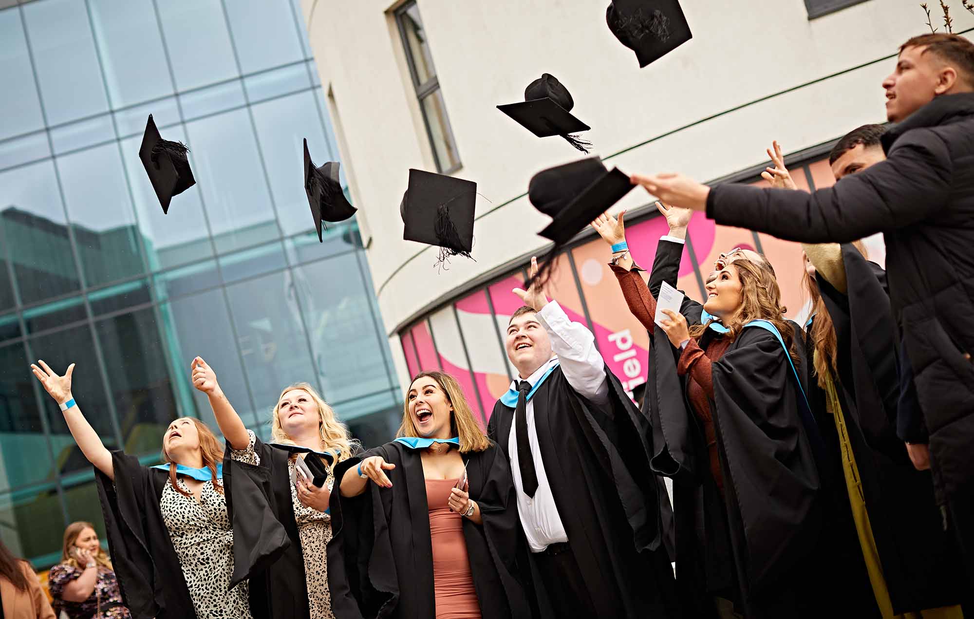 Graduates throwing hats in the air for alumni pages
