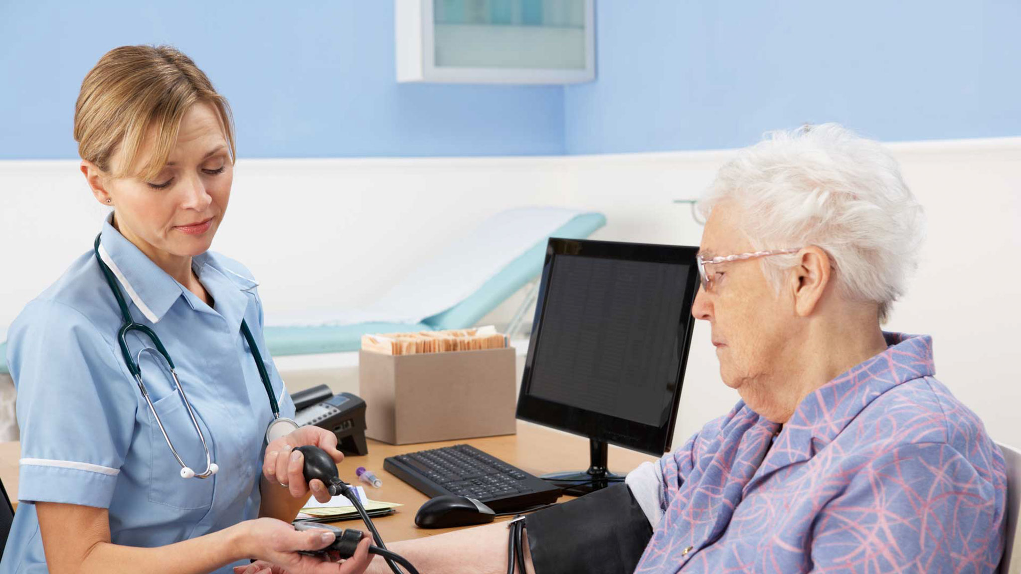 A nurse taking an elderly ladies blood pressure