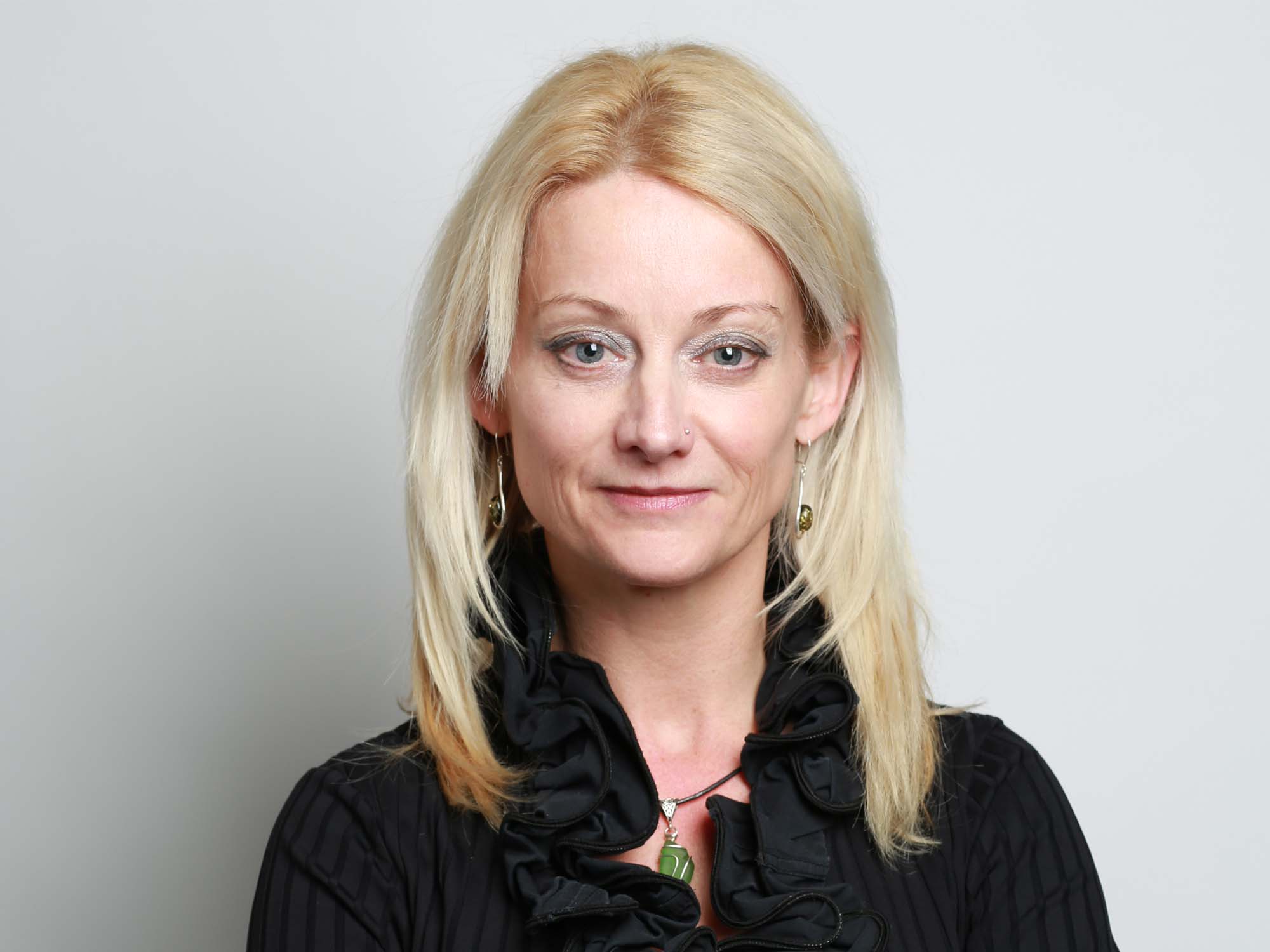 Professor Louise Rose, wearing a black top and posing with arms crossed