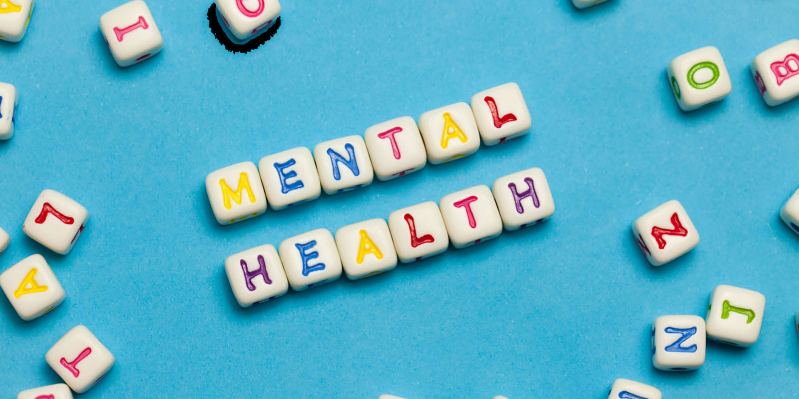 Letter dice on a light blue background spelling out mental health