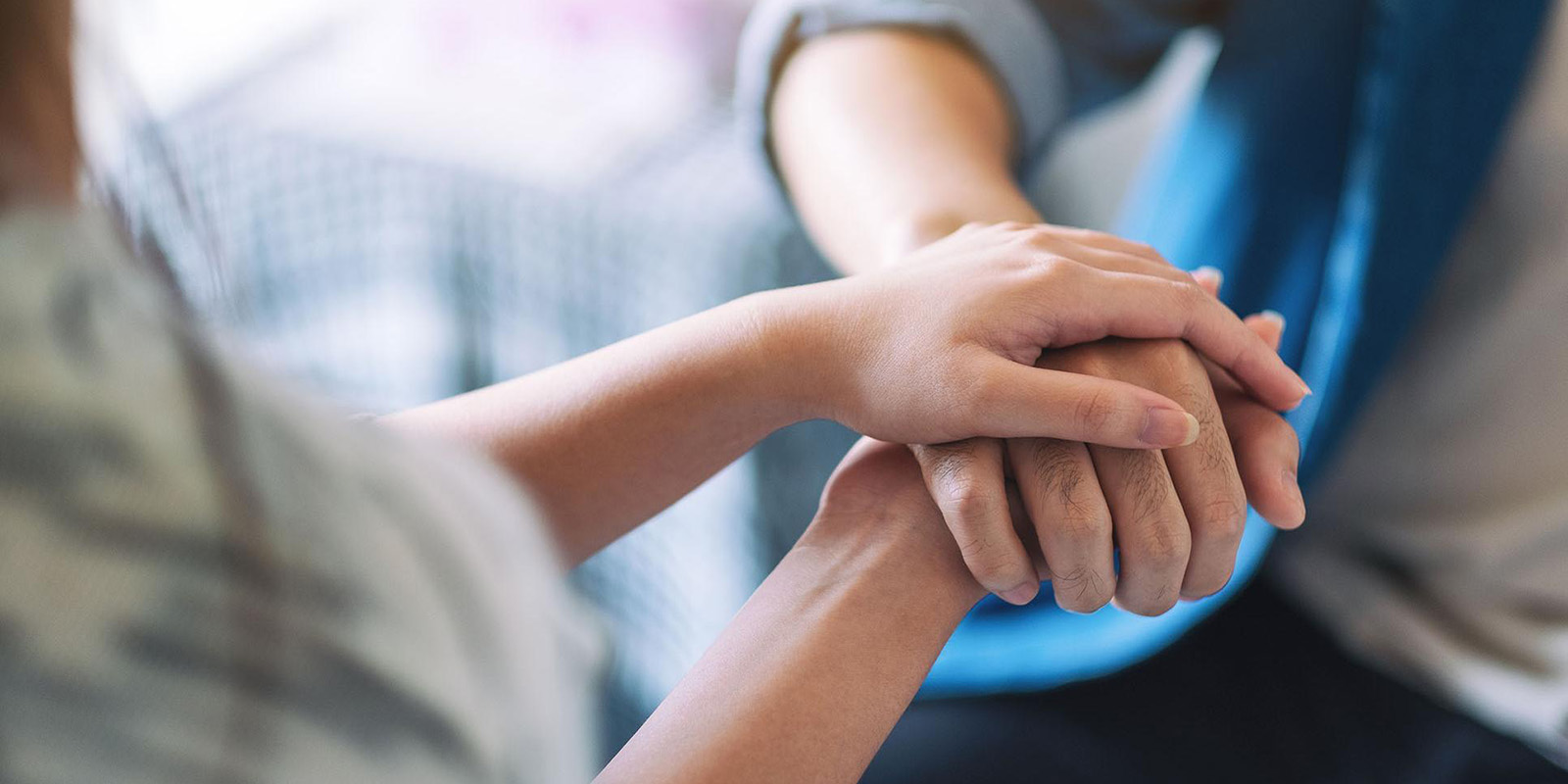 An elderly hand being held kindly by another pair of hands