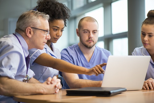 A group of nurses sitting around a computer