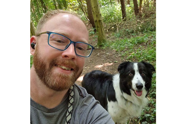 Photo of Josh Hodgson posing with a black and white dog