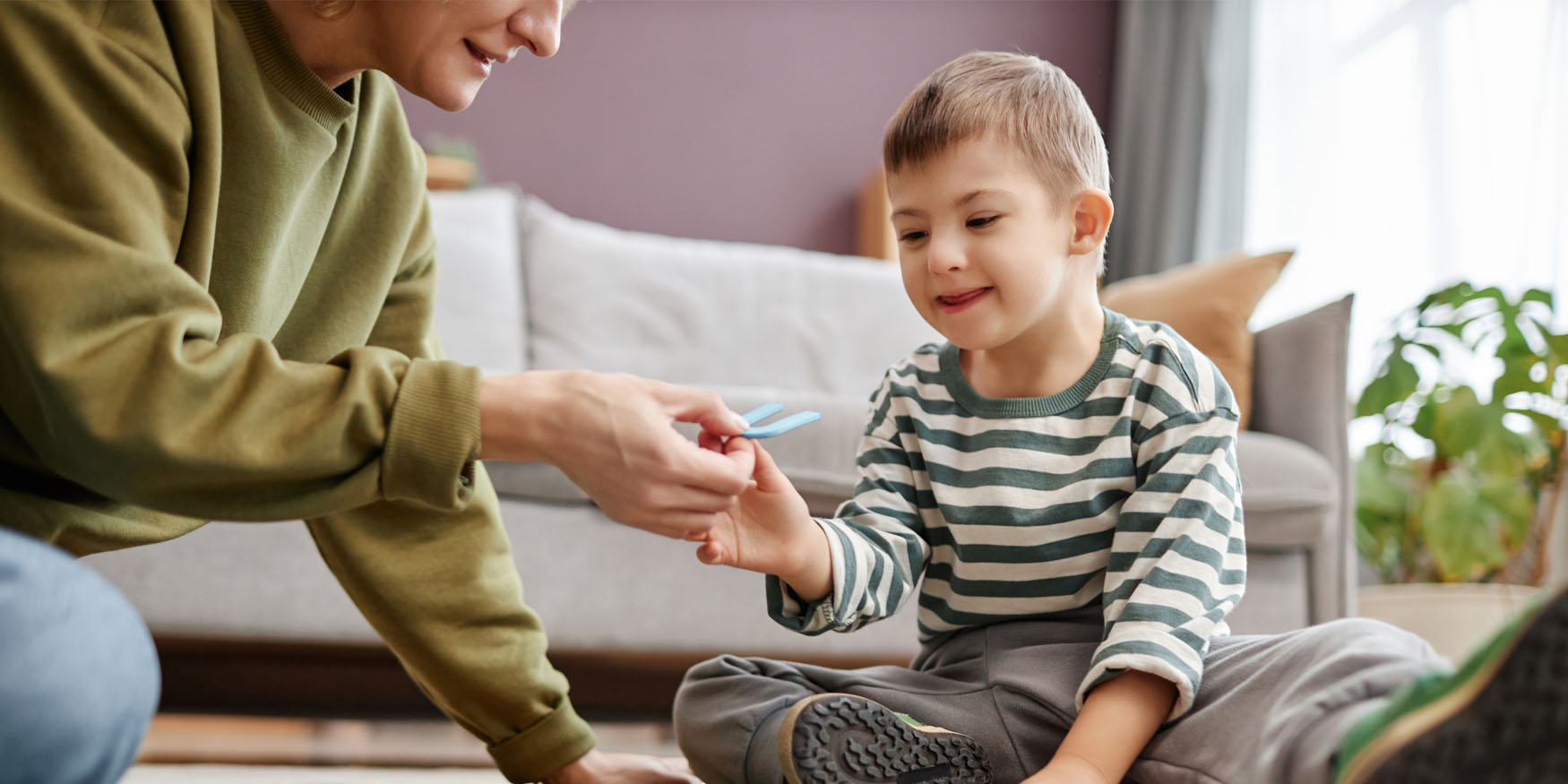 An adult and small child sitting on the floor, interacting.
