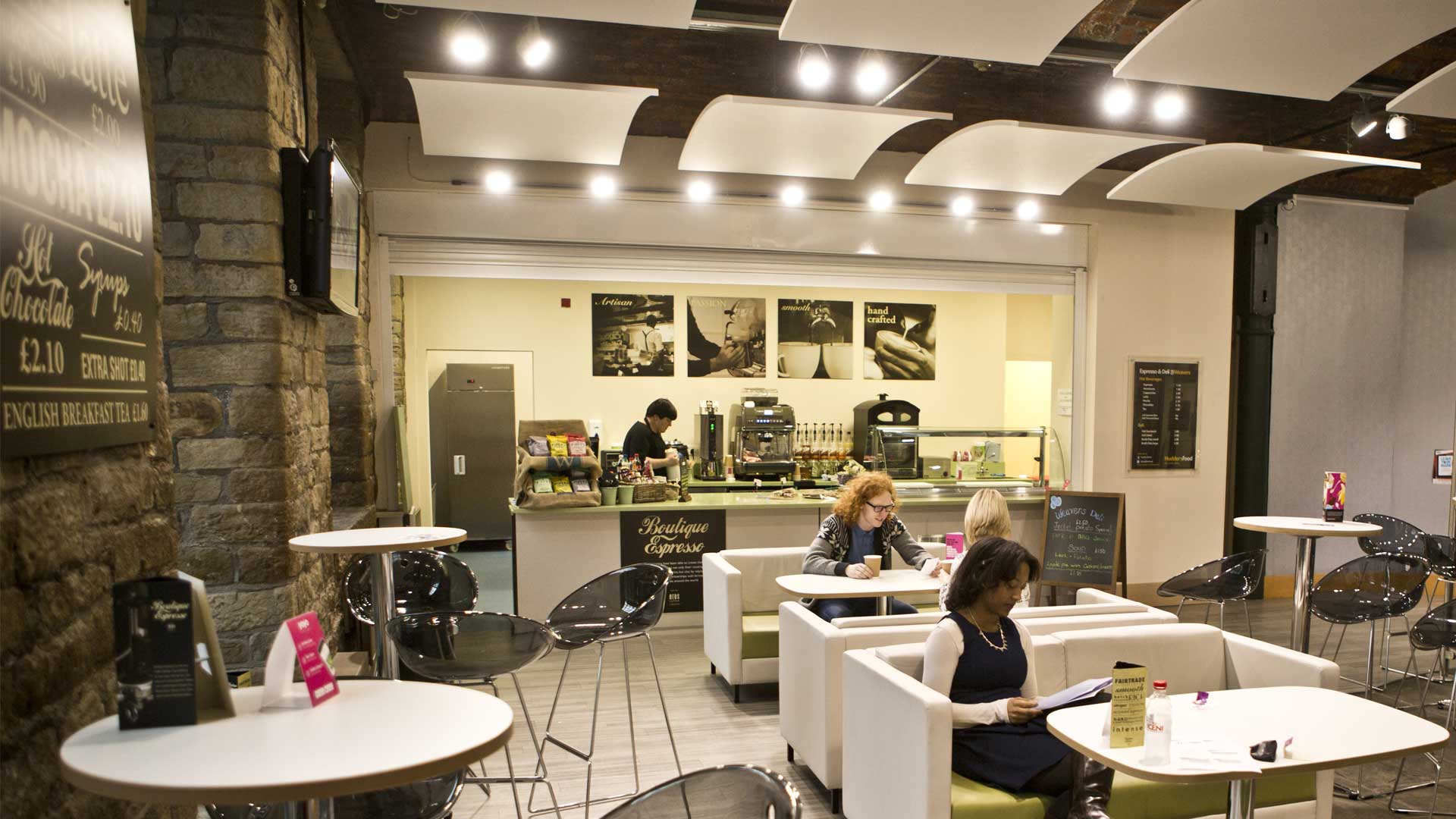 Boutique Expresso is a cafe on campus. A number of students site spaced out on couches. In the background the cafe bar can be seen.