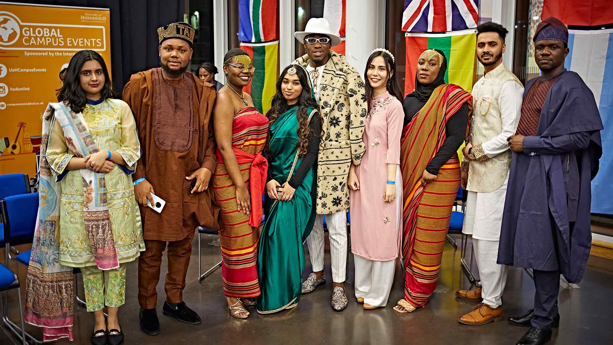 A group of students stand together in traditional clothes at the Global Fashion Show. 