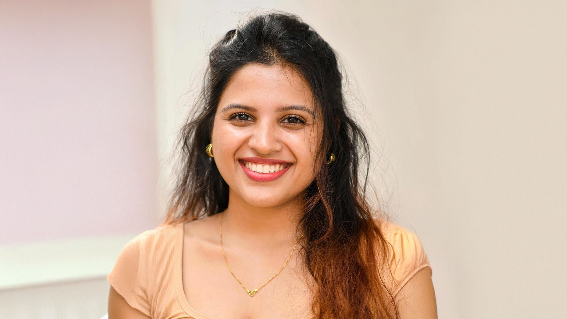 Woman smiling infront of a plain background