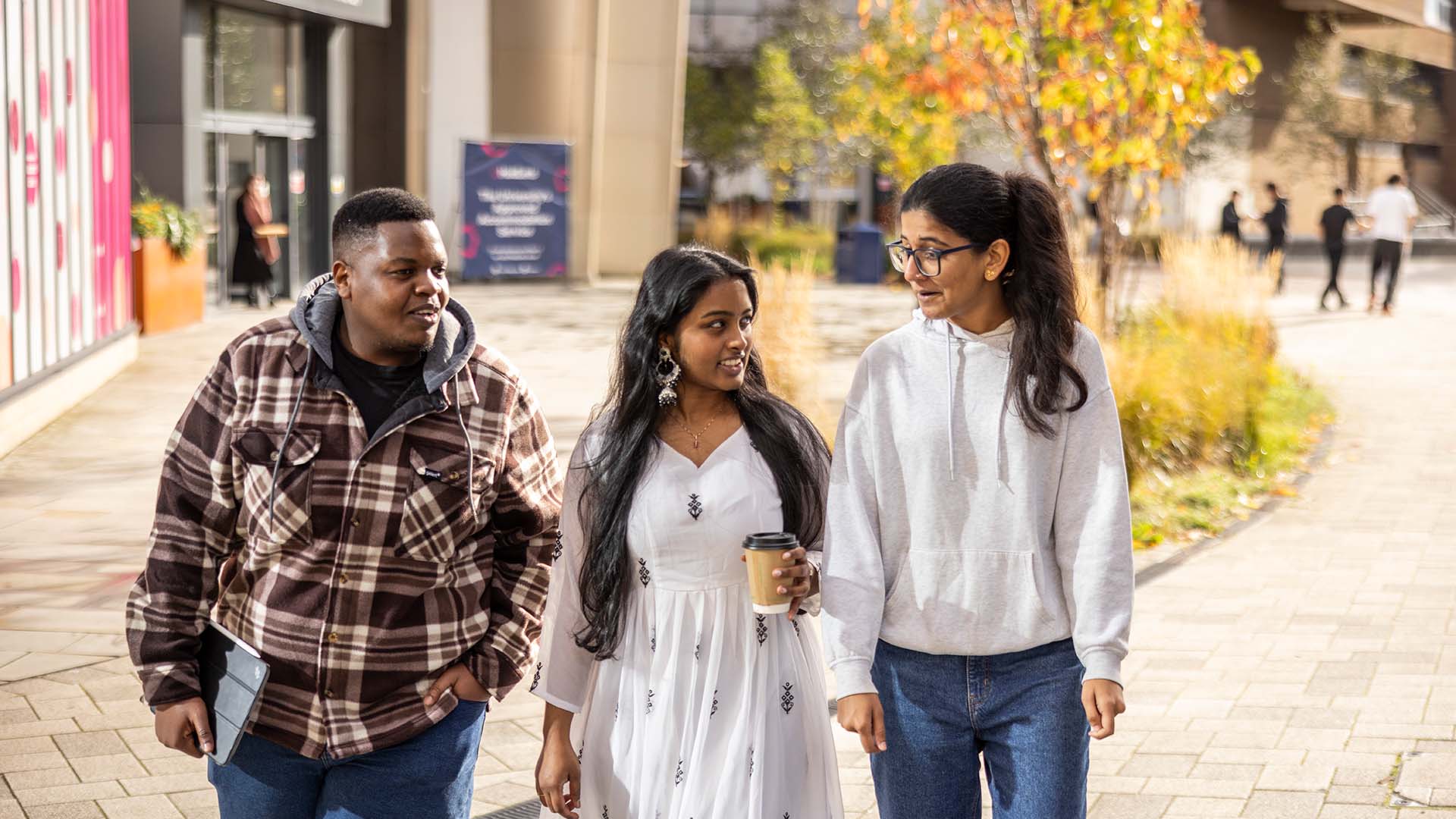 Three students walking through Huddersfield campus