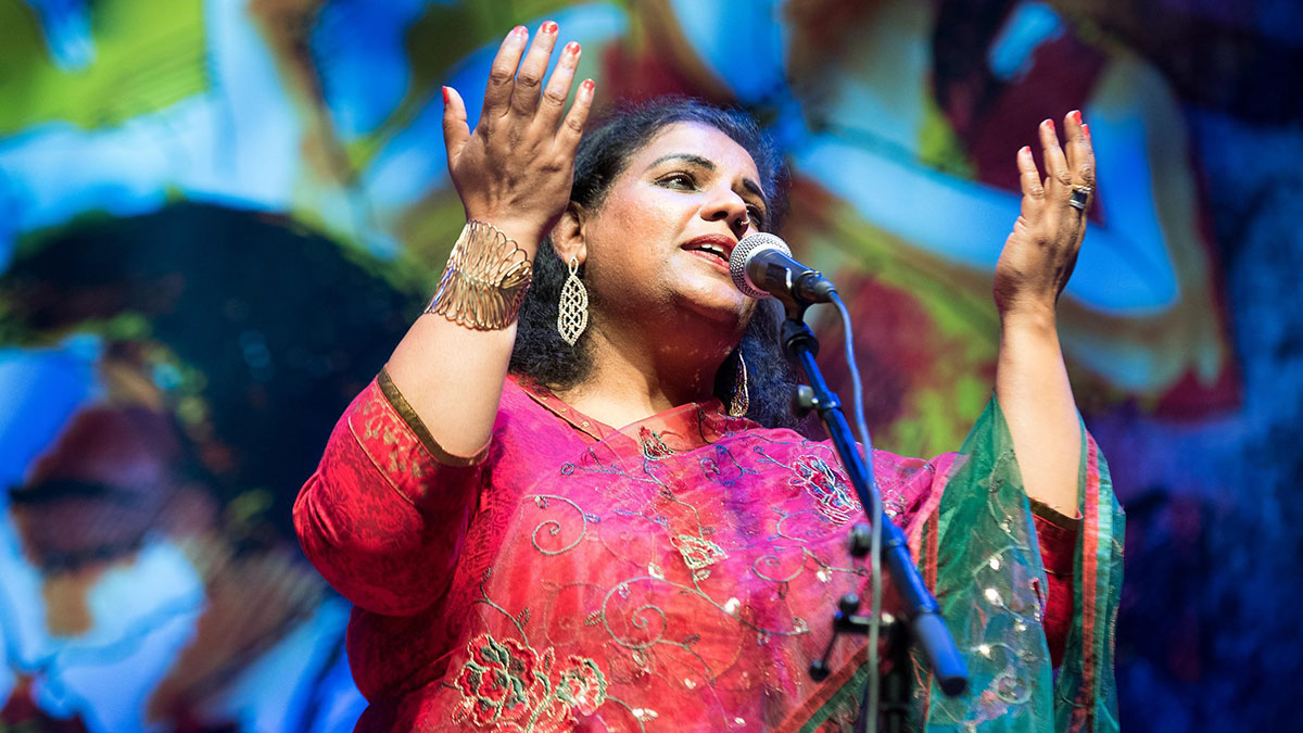 Deepa Nair Rasiya performing on stage, arms raised