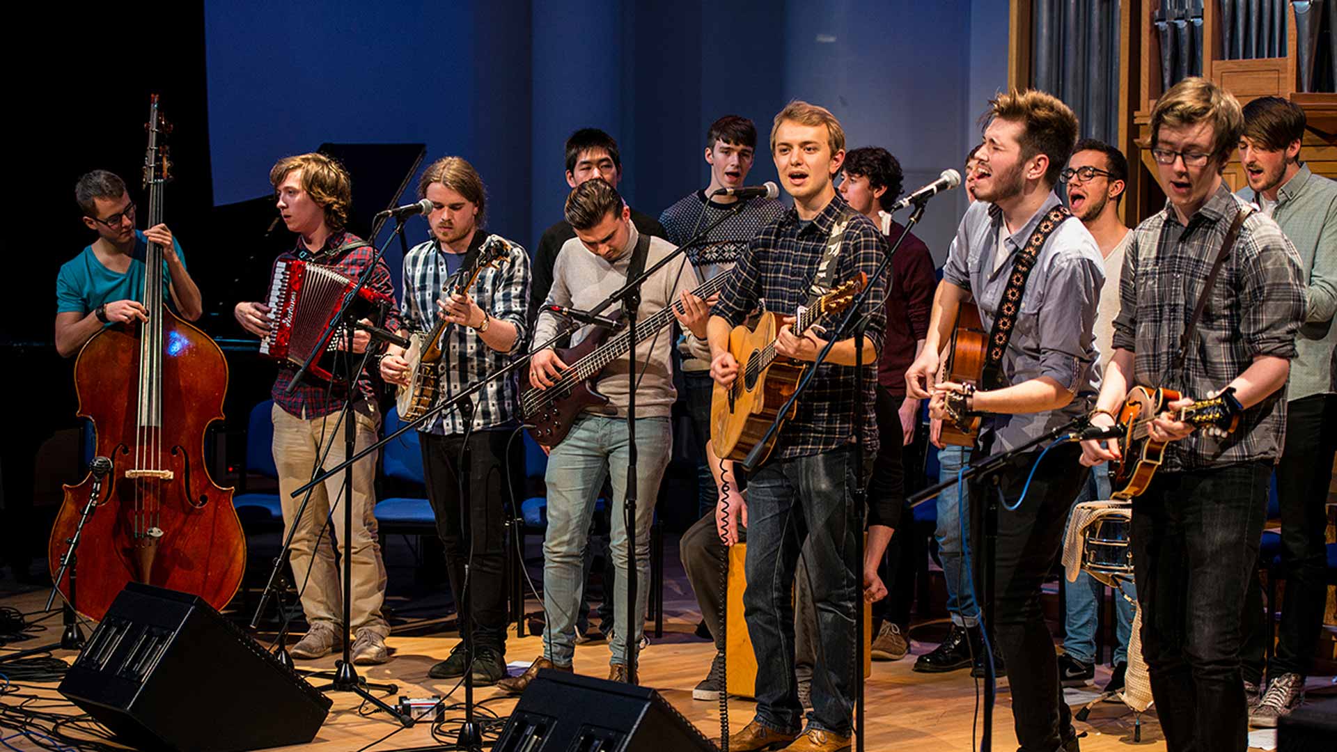 A folk group band singing on stage at an event.