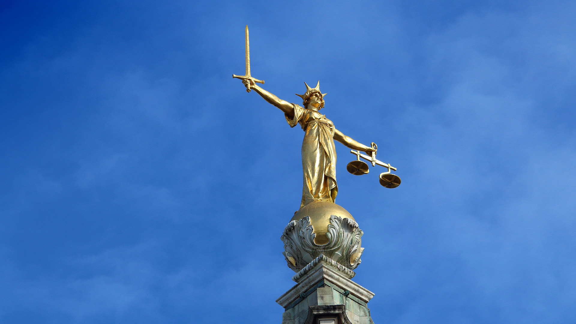 A statue with the scales of justice at the courts of justice in London