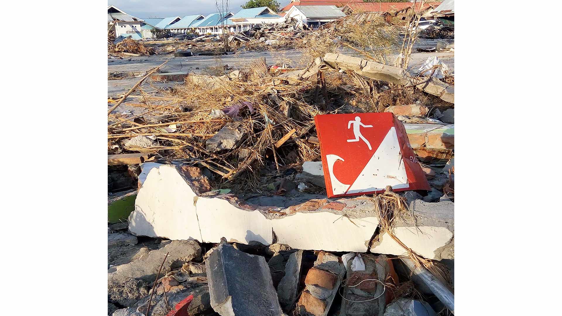 Destroyed building and tsunami warning sign