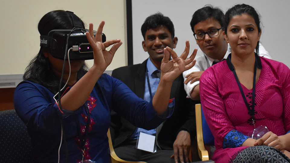 A student wearing a virtual reality headset with some students looking on
