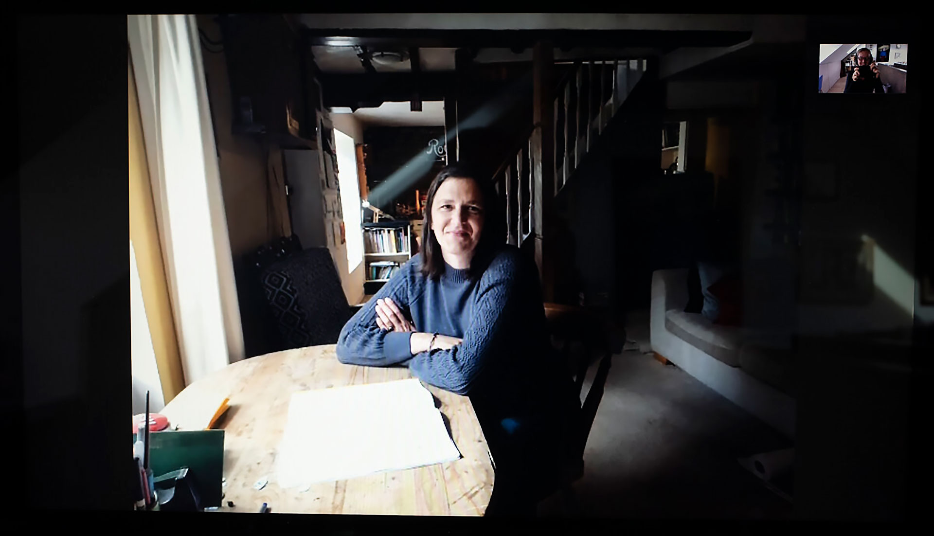 Alison sits at a table lit by the window whilst the rest of the room is in shadow. The table is now a place for craft and home schooling.