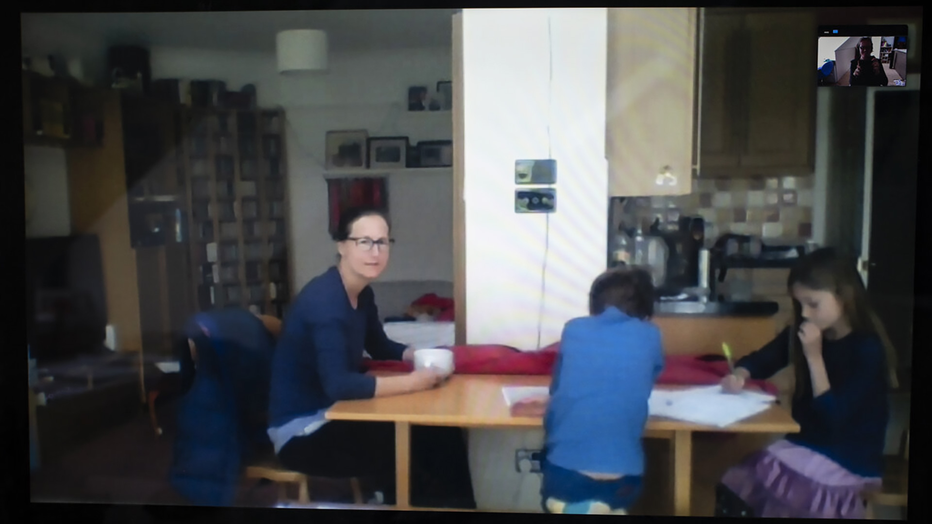 Sophy, her son and daughter sit at a table between the lounge and kitchen whilst the children do schoolwork.