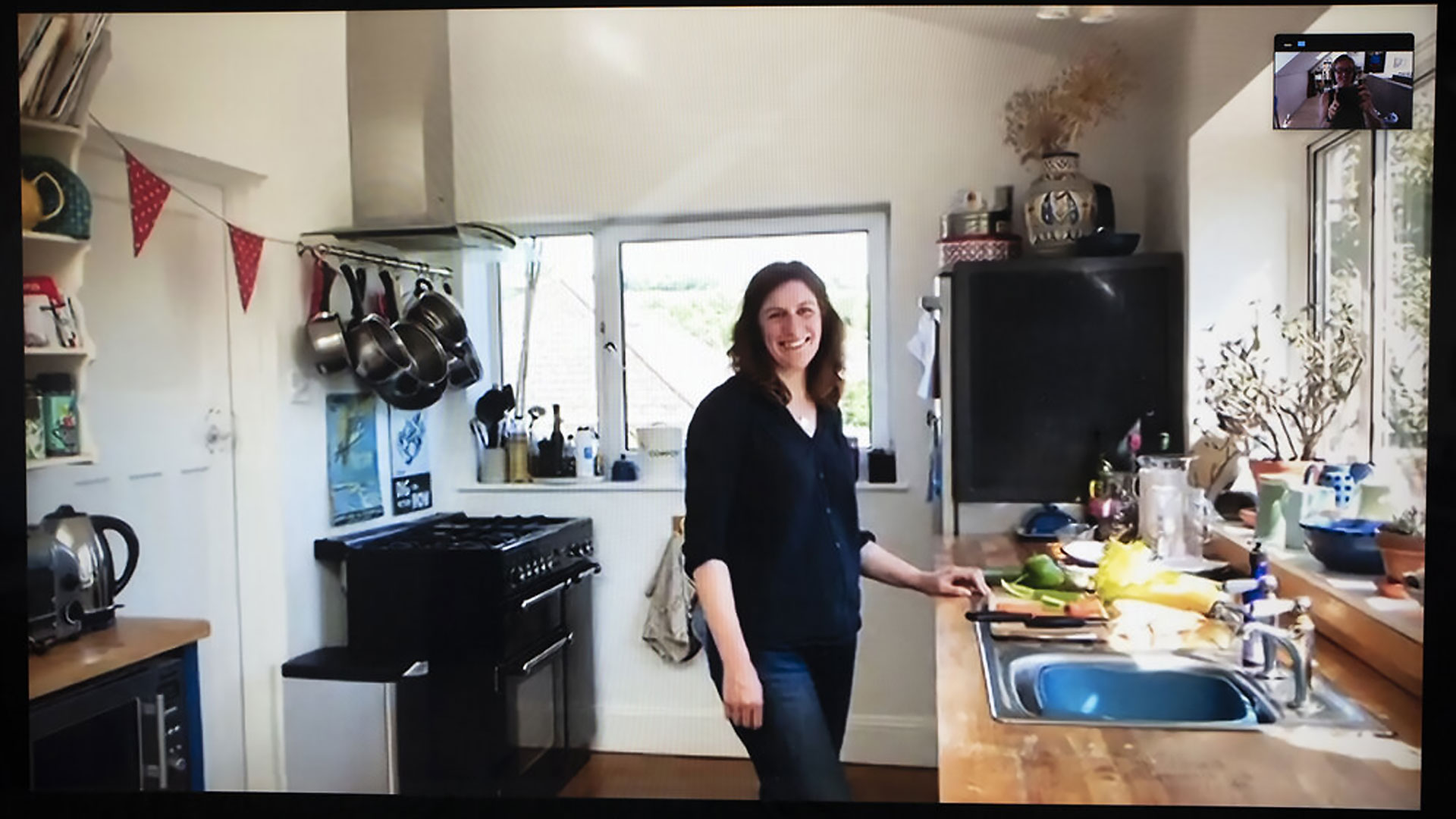 Cathy standing in the Kitchen by the wooden countertop and sink whilst making snacks.