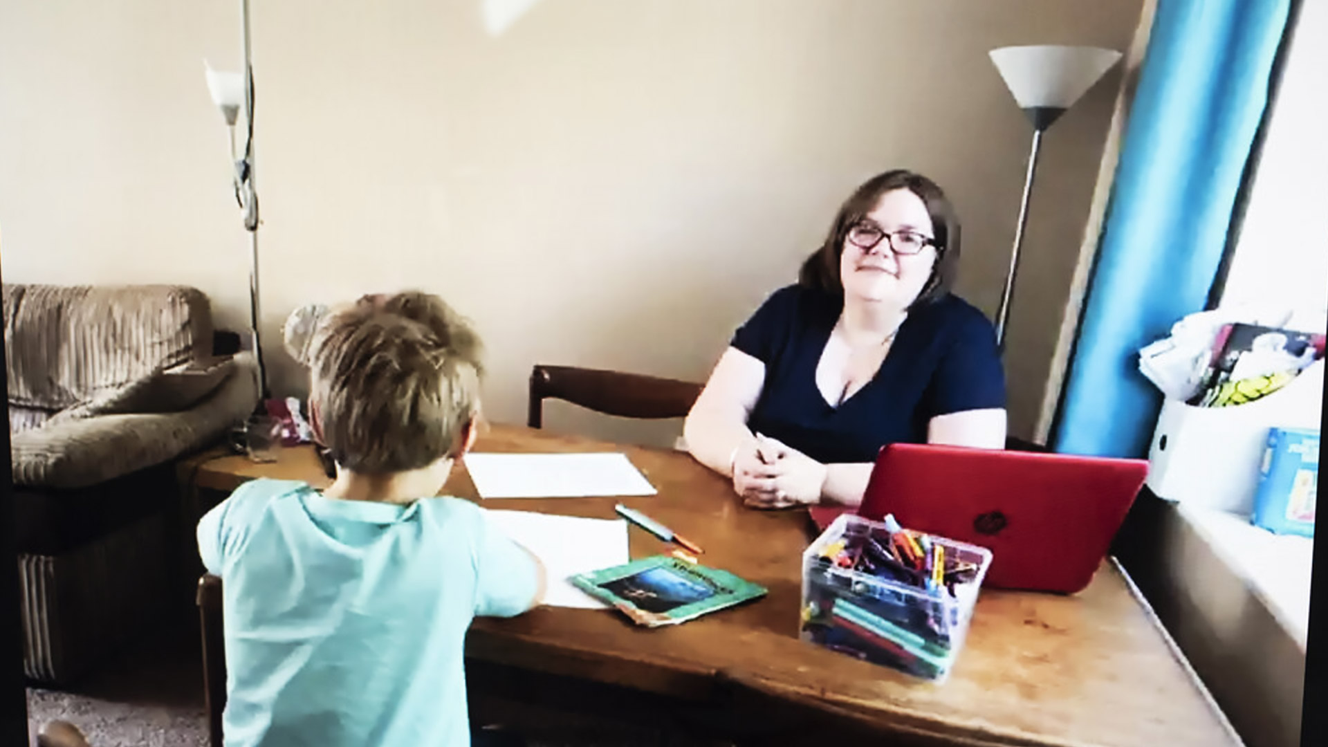 Mel works with her son at the living room table