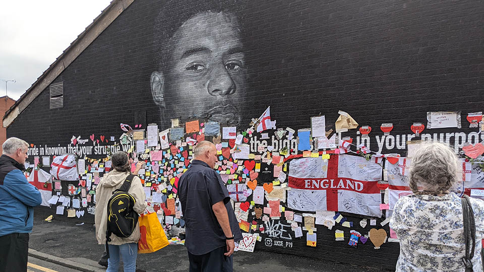 The mural of Marcus Rashford in Manchester with people looking at it
