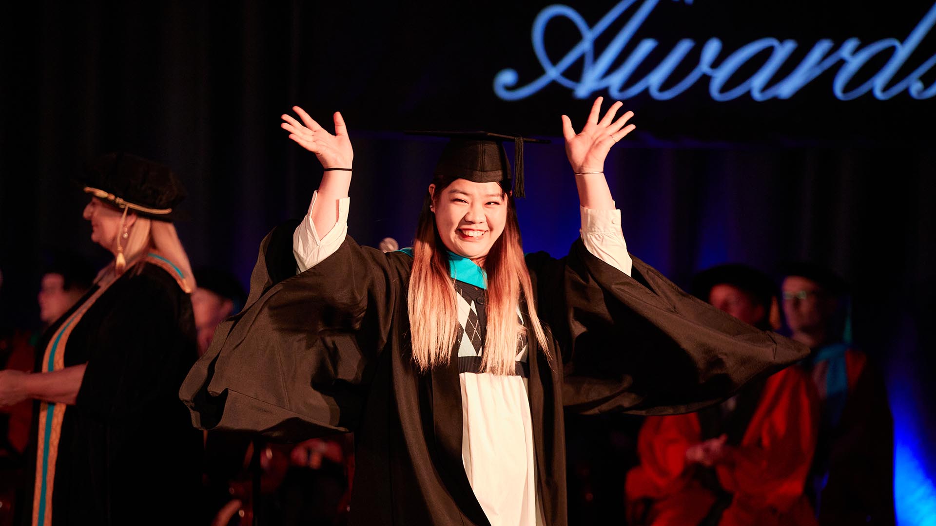 A student celebrates getting her degree by waving her hands wackily