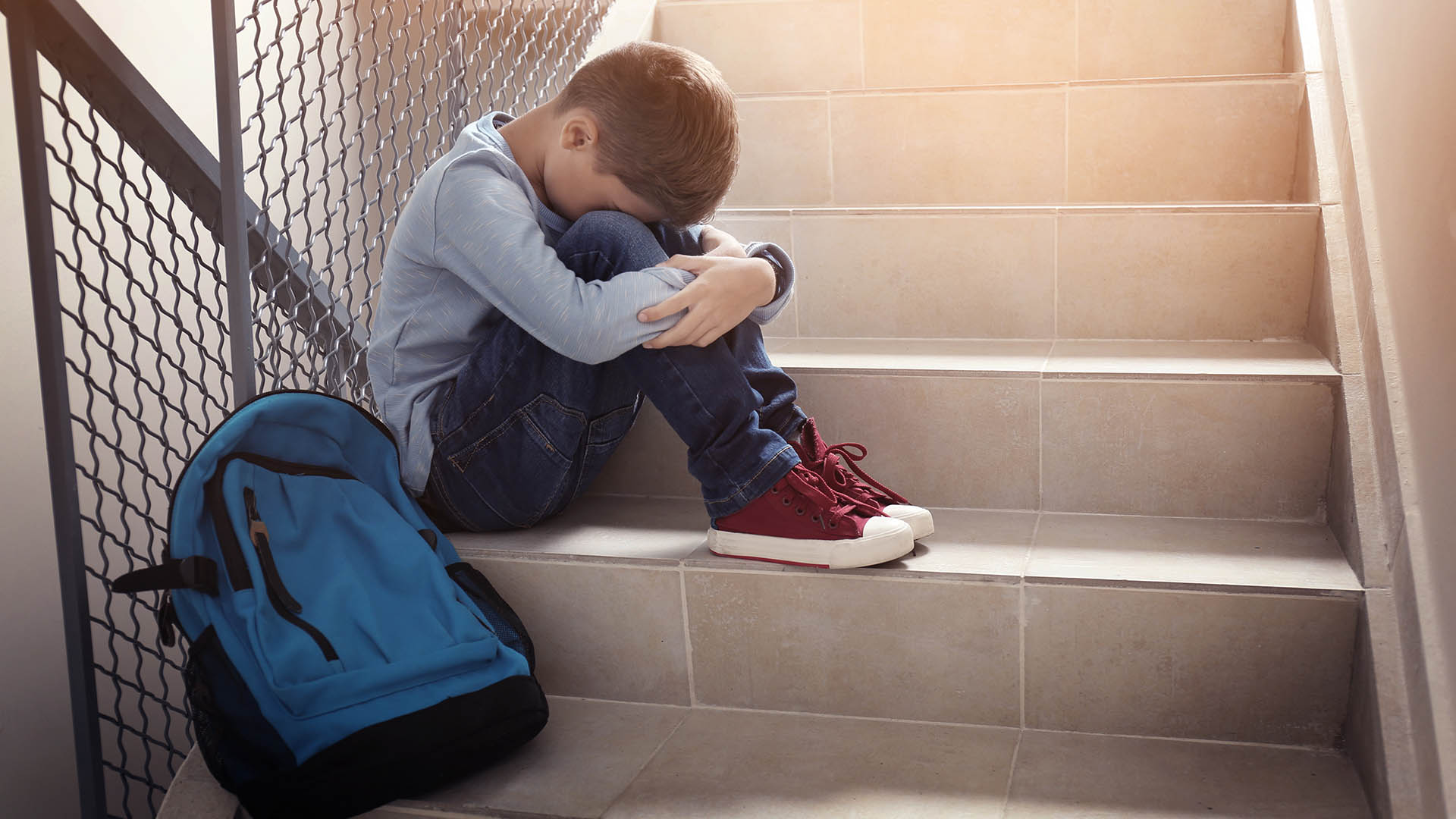 An unhappy child sits on some stairs