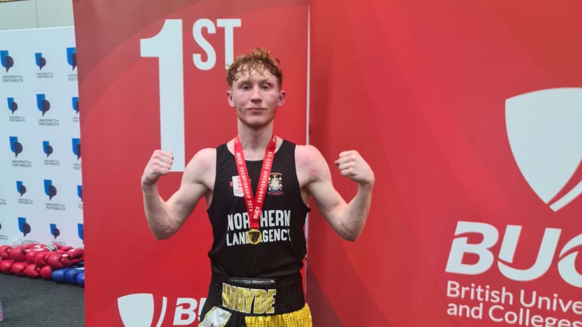 Boxer Wayde Griffin celebrates his win in front of a sign that says first