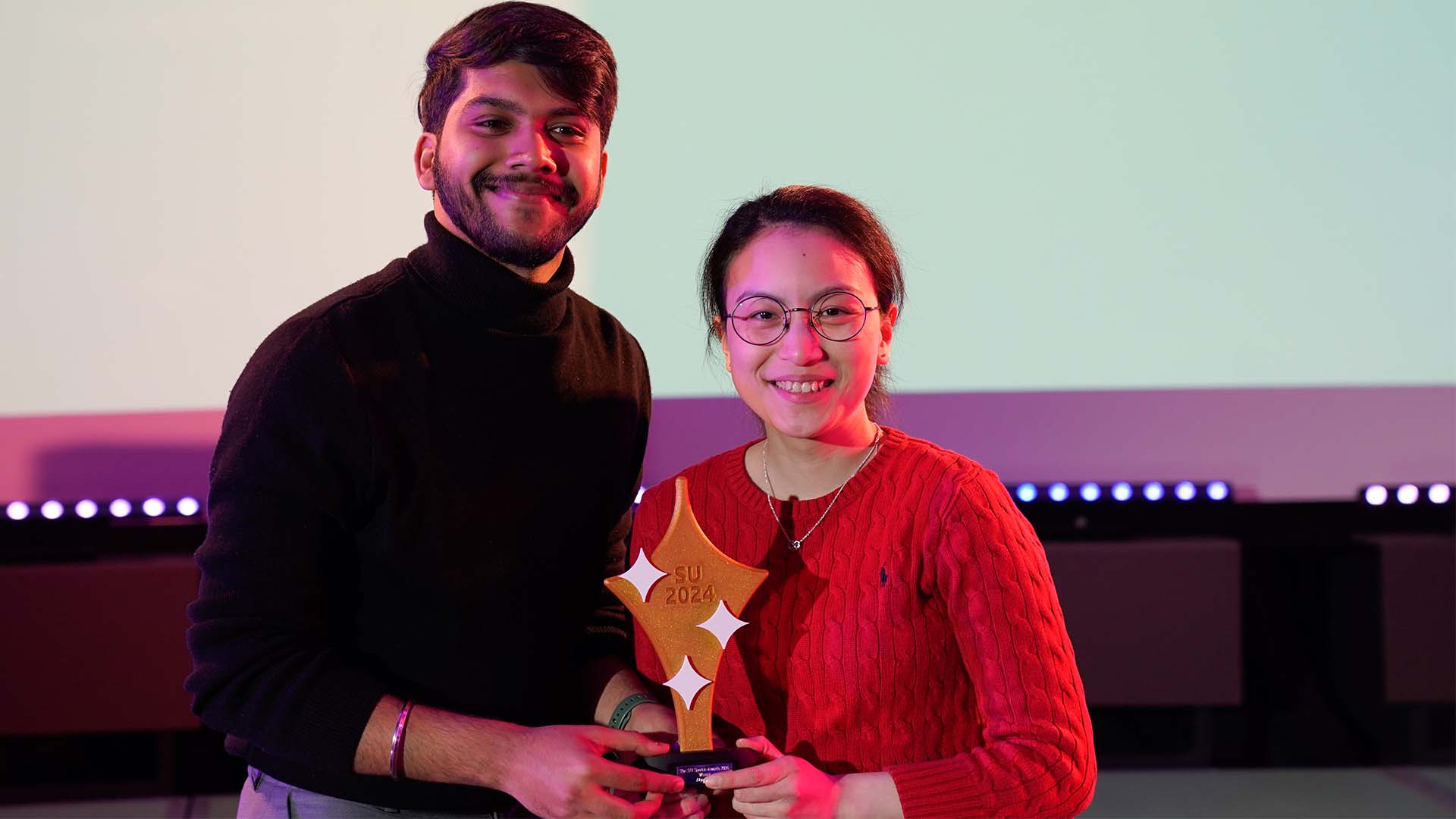 Elyse Woo stands with another student and a trophy