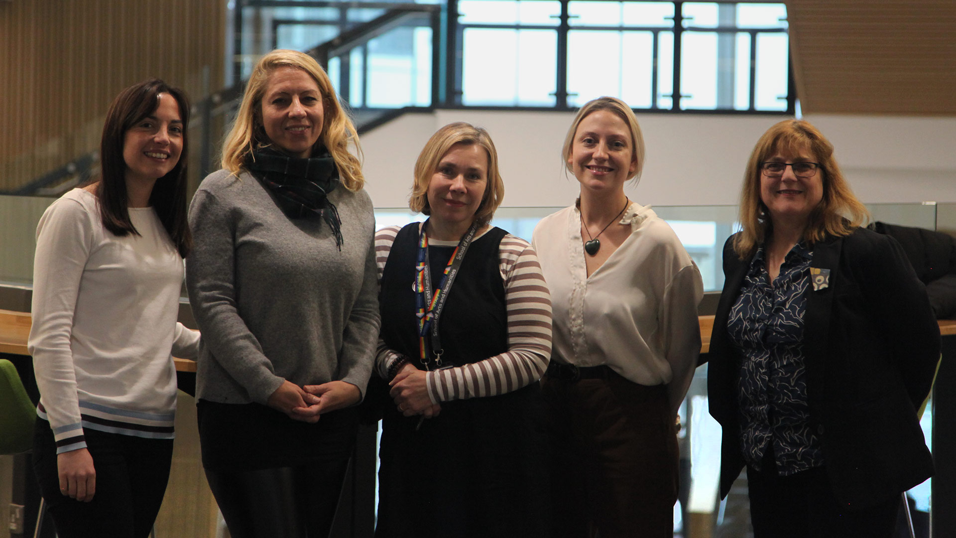 a group picture of five women standing in a row