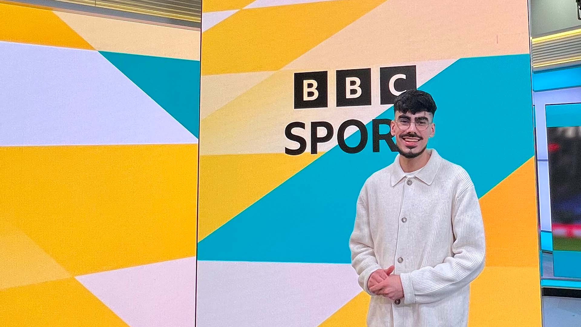 Srosh Khan stands by a sign saying BBC Sport in a studio