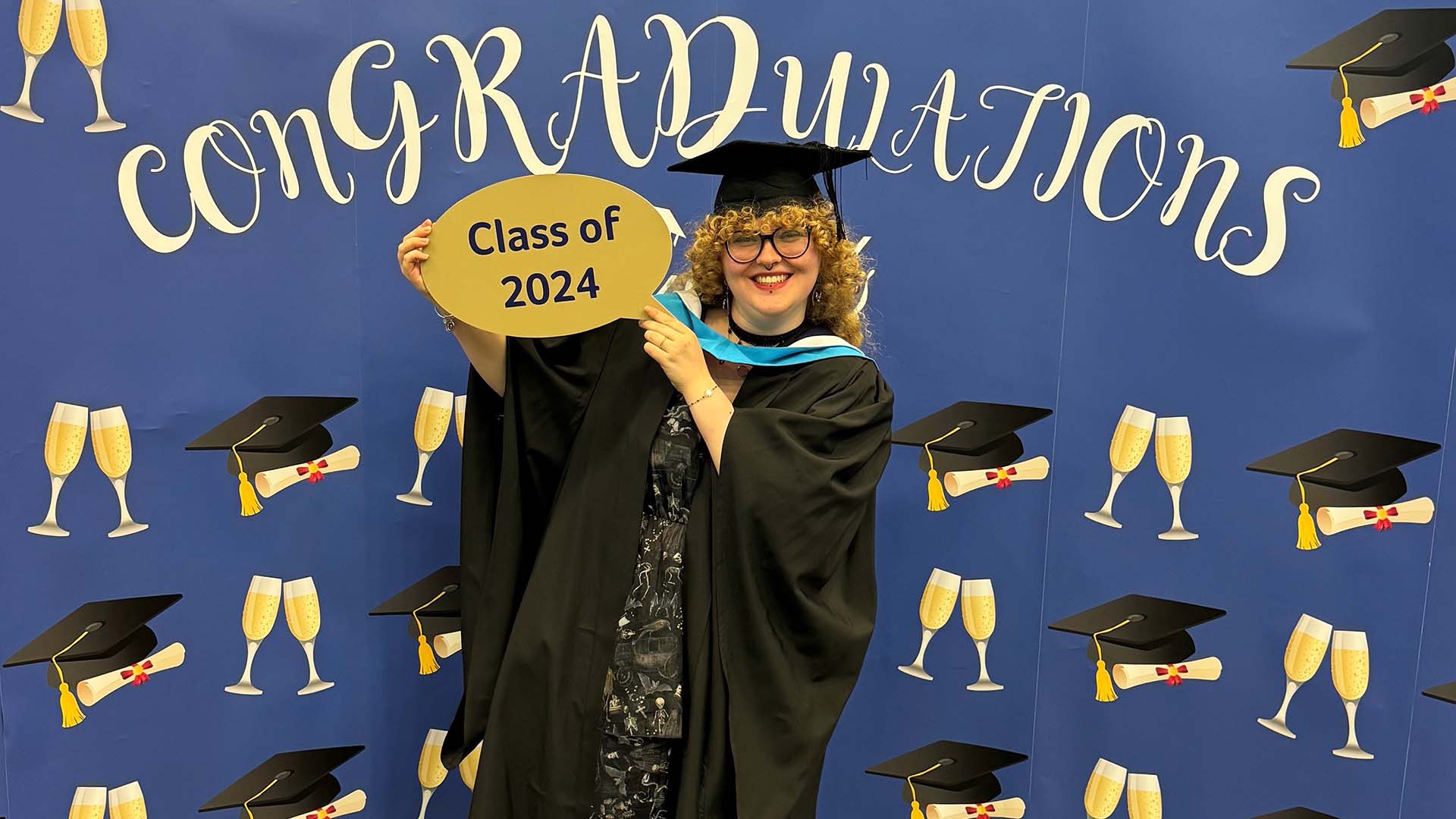 Megan Horner celebrates her graduation in front of a display panel