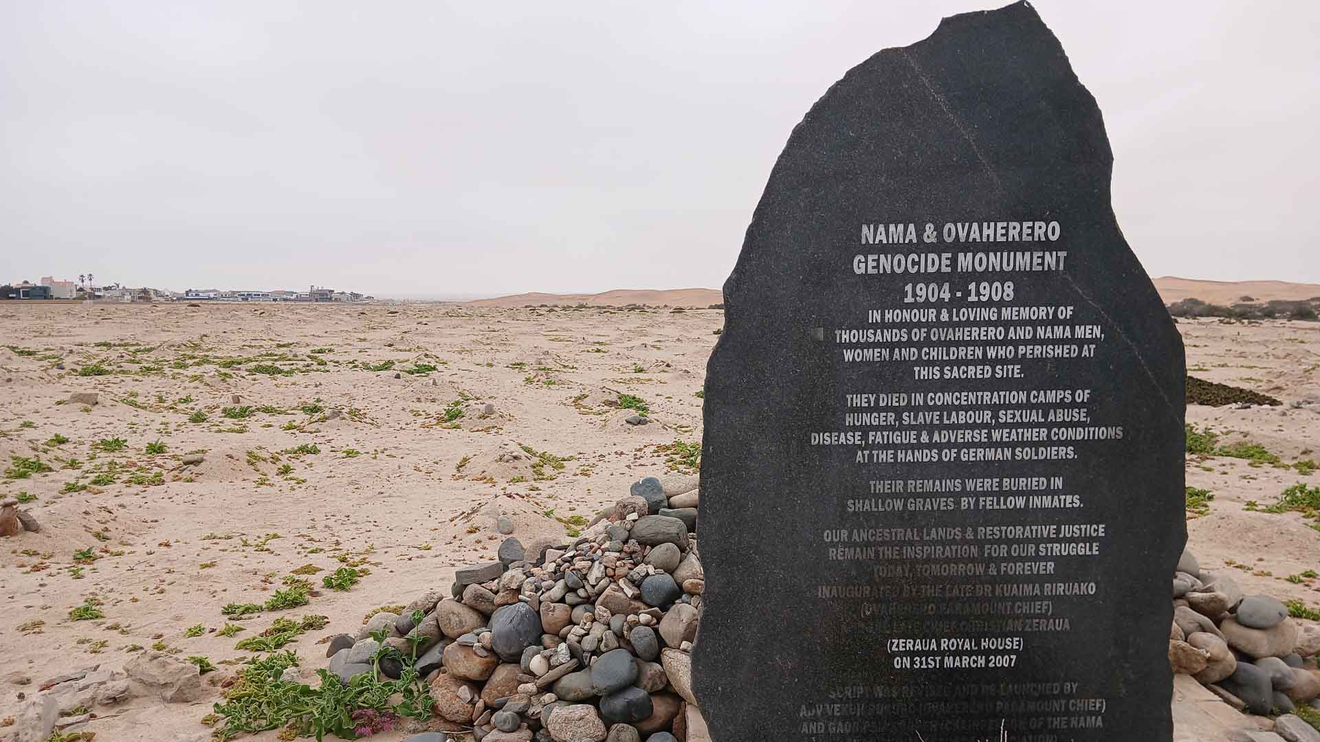 A stone describing the grave sites and genocide in Namibia stands in the desert