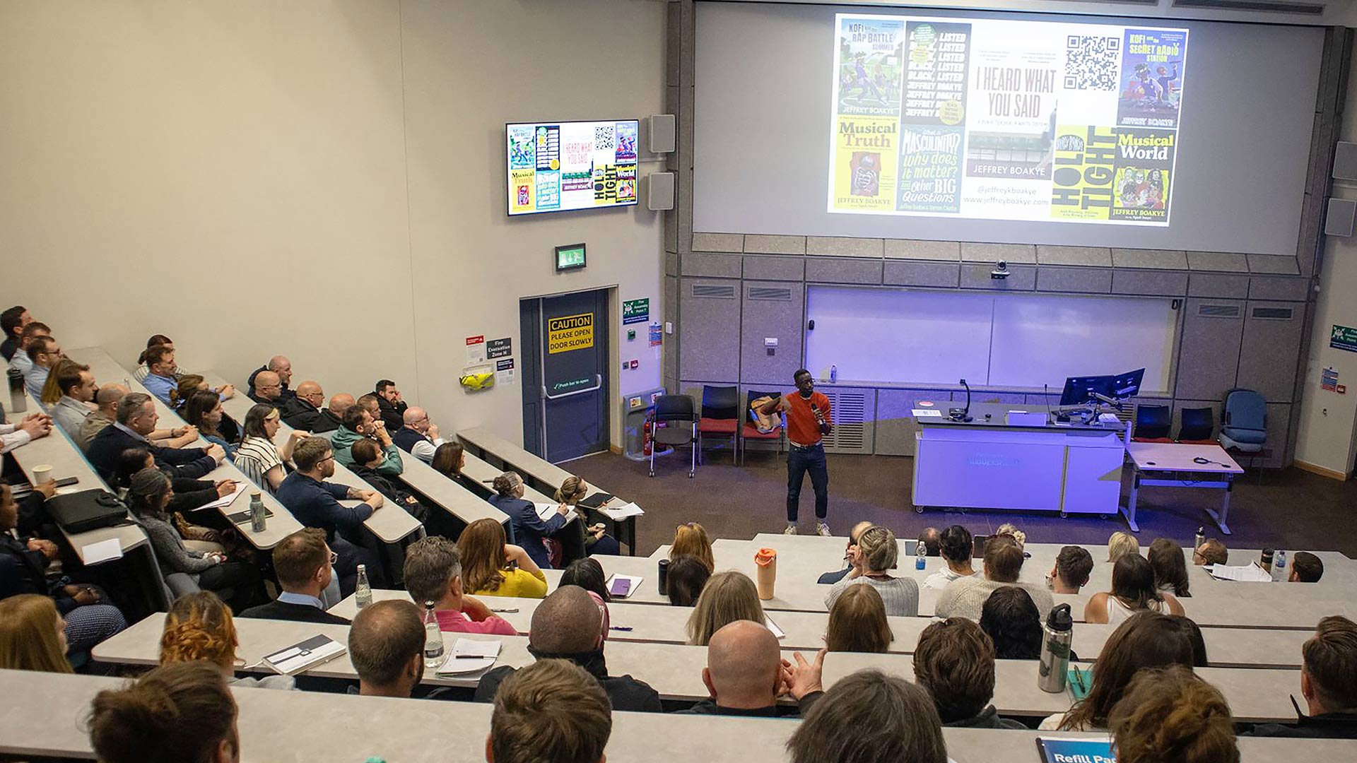 People sitting in a lecture theatre with someone presenting at the front