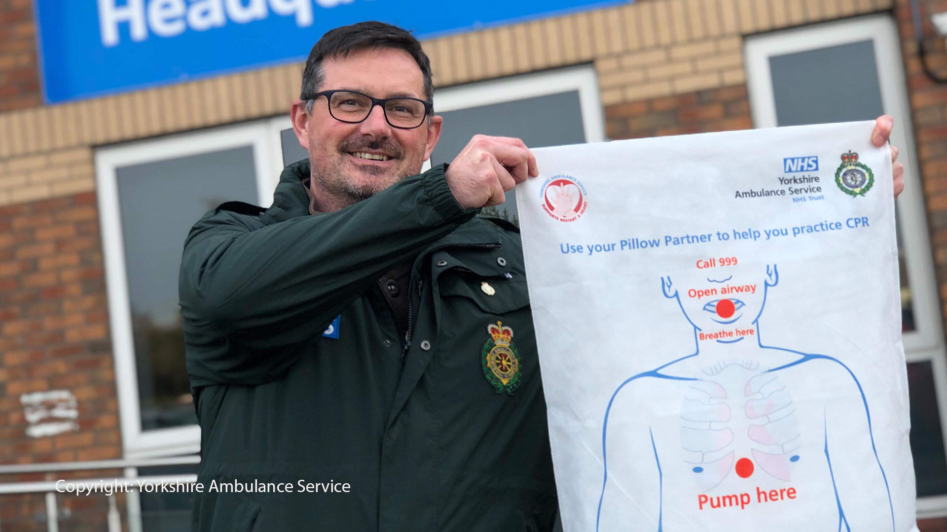 A man holds up a CPR diagram in various languages