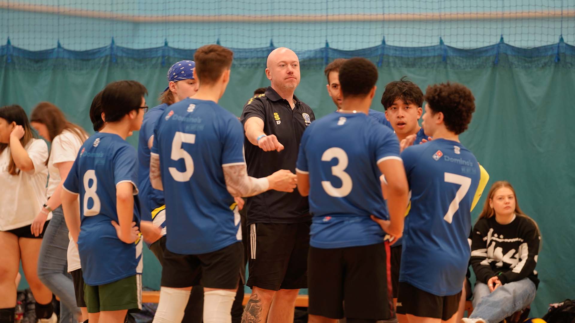 A coach talks to student volleyballers