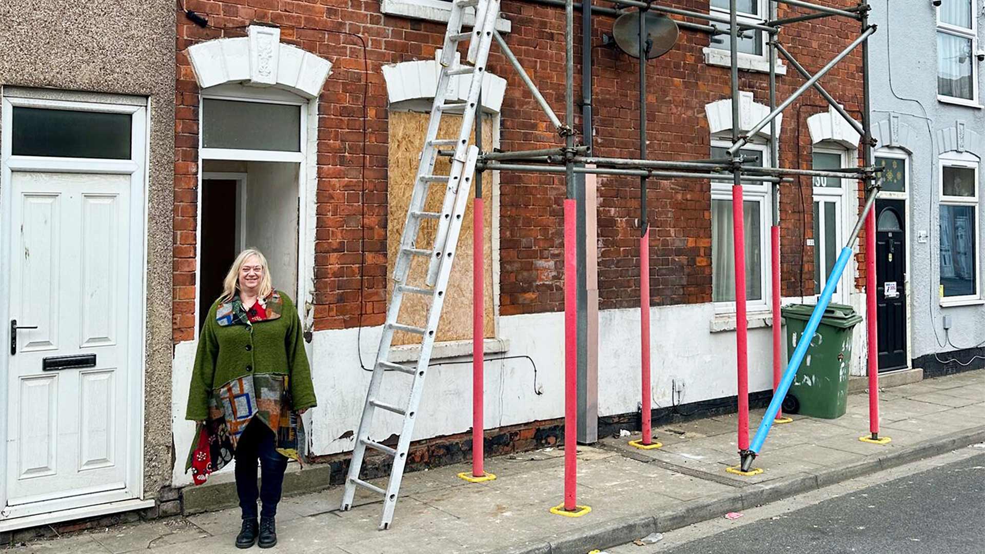 A woman stood in front of a terraced house which is being renovated