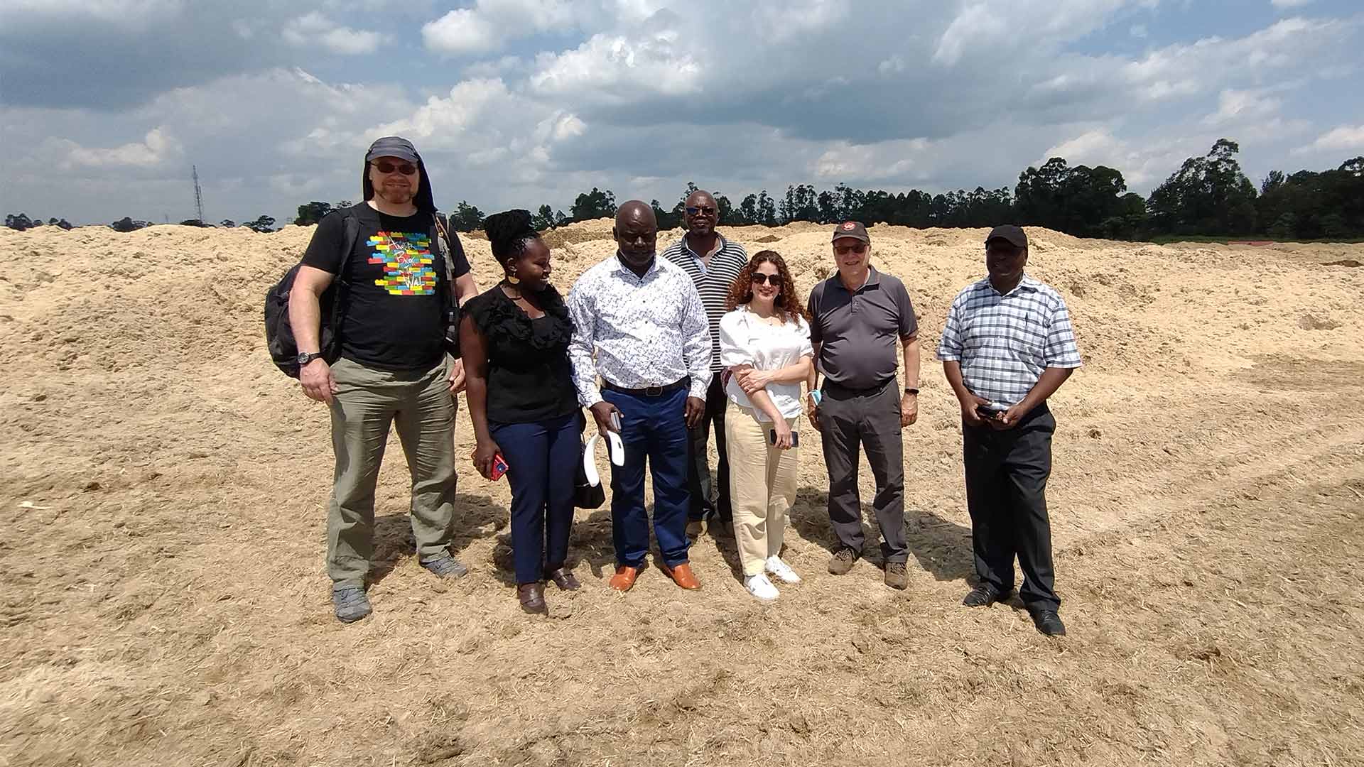 A group of people standing on a mound of sugarcane waste in Kenya