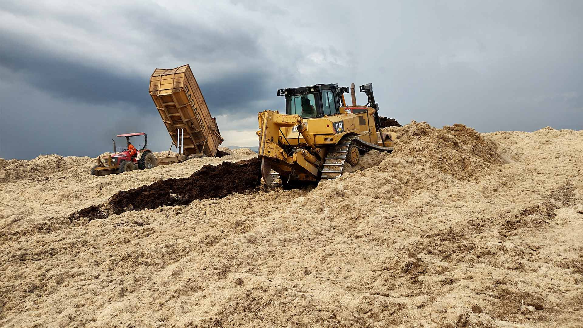 Machinery moving mounds of sugarcane waste in Kenya