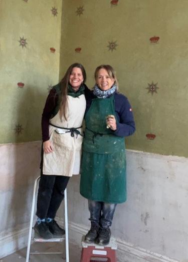 Louise and Angeliki in front of the wallpaper after revealing it.