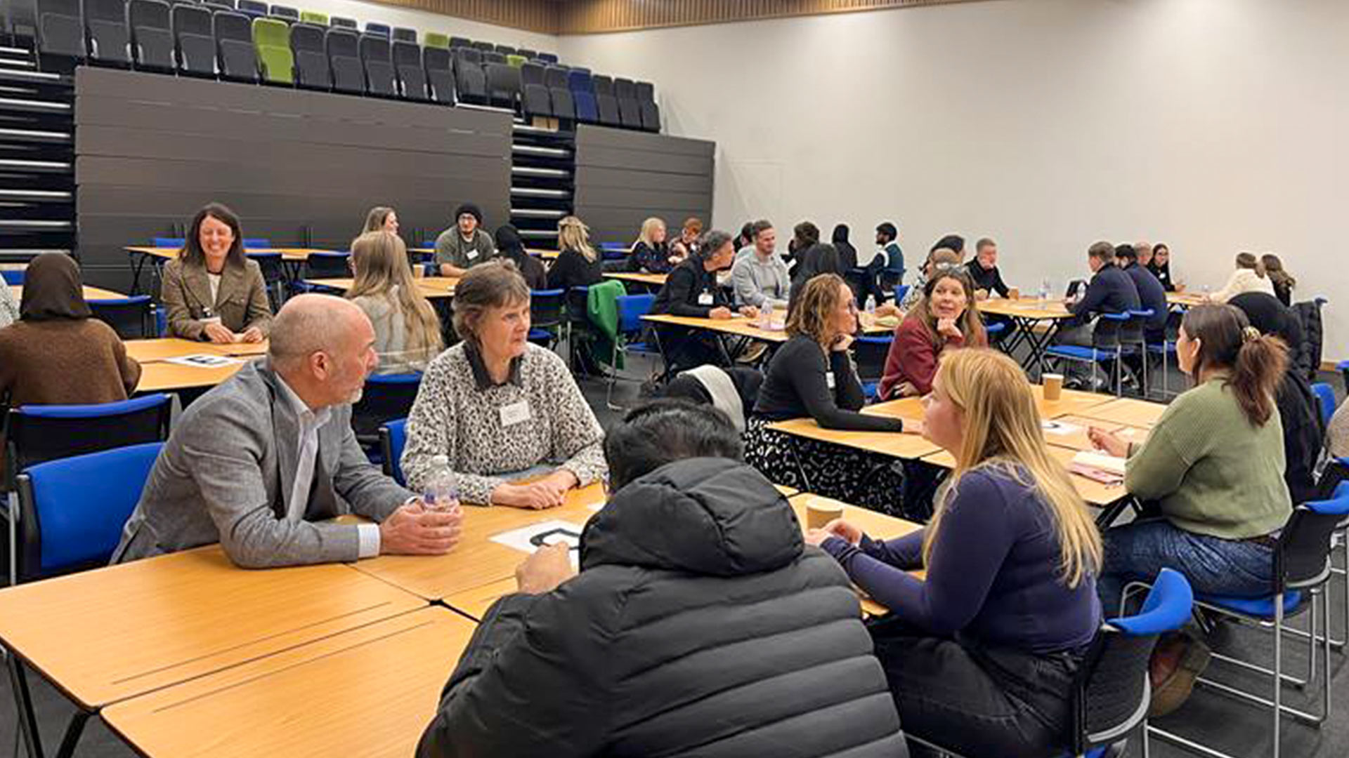 A group of students with businesspeople sat around a table in a conference room